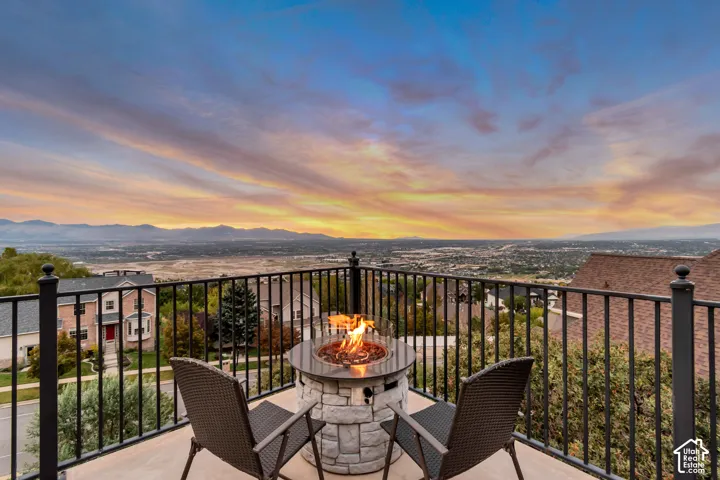 Outdoor balcony with a stone-finish fire pit, black metal railings, and a wide-ranging cityscape