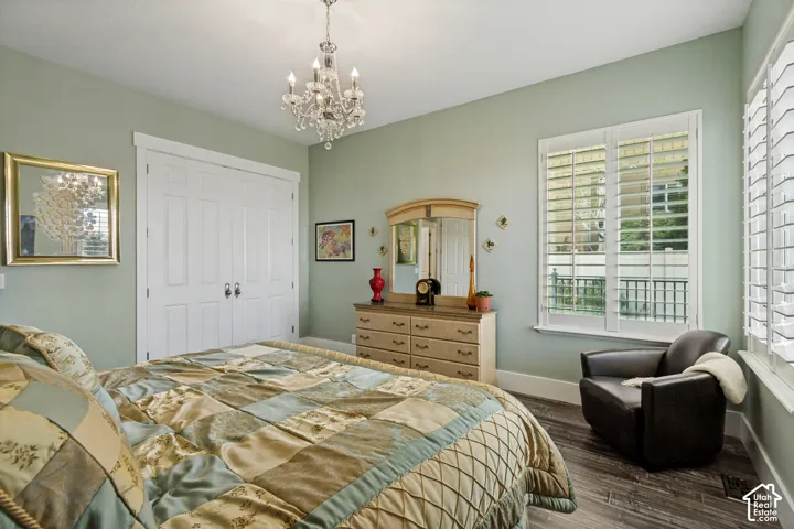 Wood-finish flooring, white window shutters, white bi-fold closet doors, and a crystal chandelier