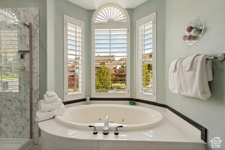Corner soaking tub with deck-mounted fixtures, surrounded by a white countertop and dark trim