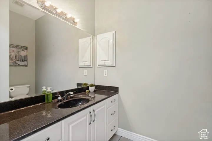 Integrated vanity with a dark countertop and undermount sink, white cabinetry with silver-tone hardware, and a large wall-mounted mirror