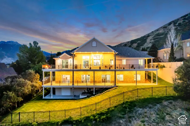 Multi-level property with expansive outdoor decks, glass panel railings, and a fenced, sloped yard