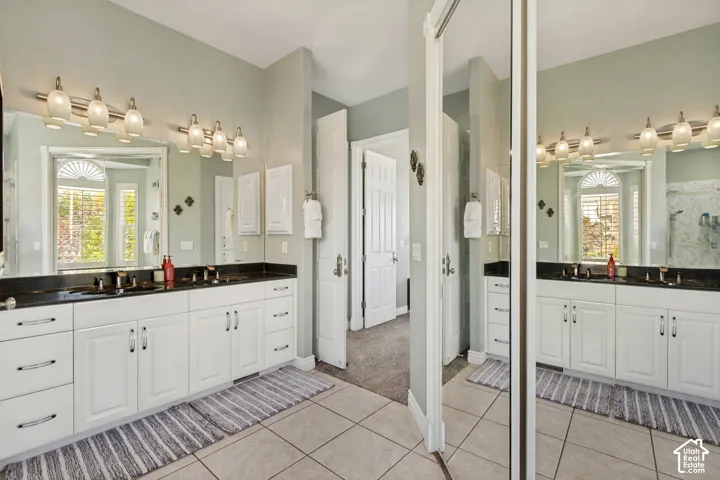Dual vanity with white cabinetry, dark countertops, and individual sinks