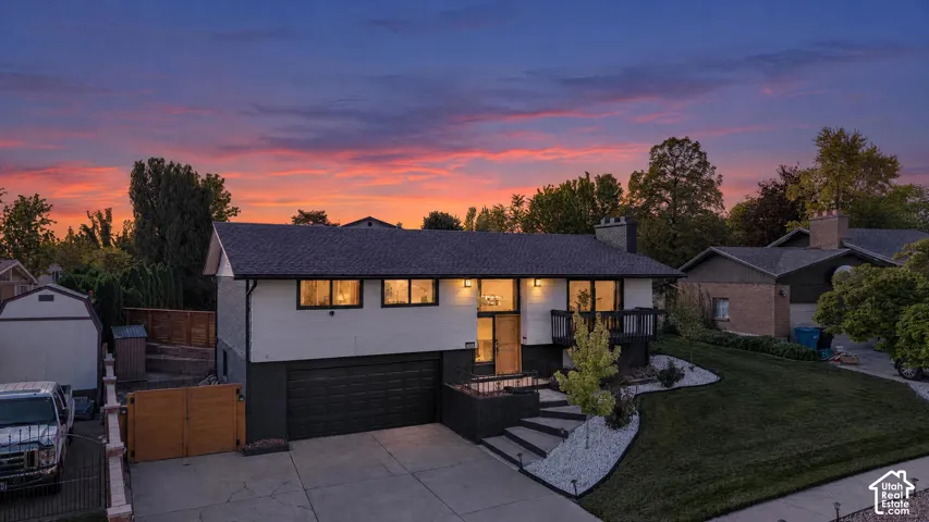 Modern architectural design with a striking black garage door and white exterior, illuminated by recessed lighting