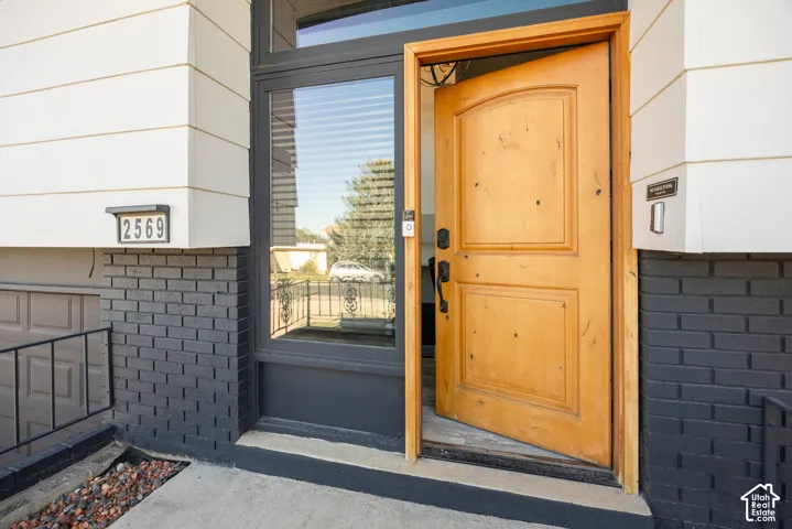 Welcoming entry featuring a solid wood paneled door with oil-rubbed bronze hardware, framed by a transom window above and flanked by mixed-material siding