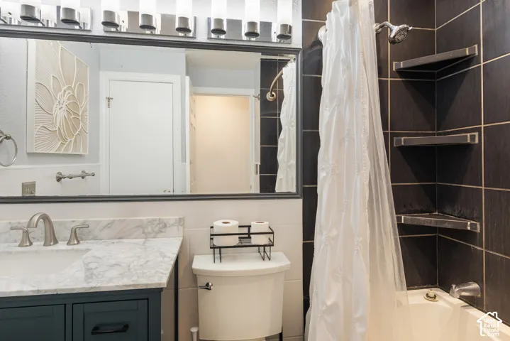 White ceramic bathtub with dark tiled surround and built-in corner shelving