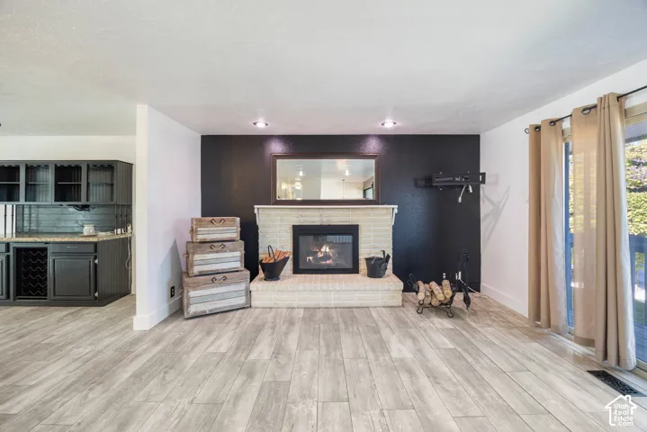 Spacious living area showcasing wood-finish flooring, a gas fireplace with tile surround and mantel, recessed lighting, and French doors leading to outdoor space