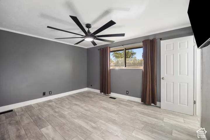 Spacious bedroom with wood-finish flooring, gray accent walls, and large windows framed by thermal-lined drapery
