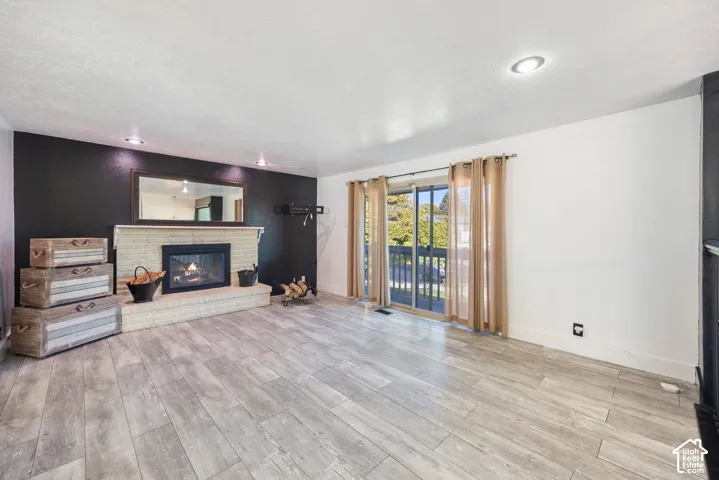 Wood-finish flooring, recessed lighting, and a brick-surround fireplace with hearth