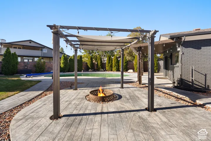 Stamped concrete patio with a pergola, string lighting, and a fire pit