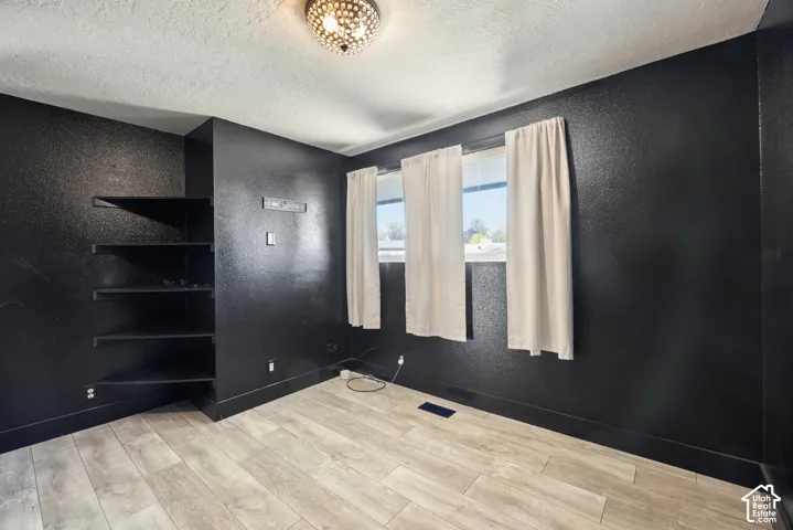 Wood-finish flooring, built-in shelving, two windows with natural light, and a decorative ceiling light fixture