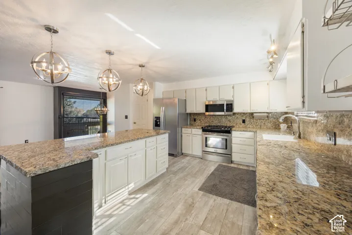 Kitchen featuring white cabinetry, stainless steel appliances, light wood-finish flooring, and granite countertops with a matching backsplash