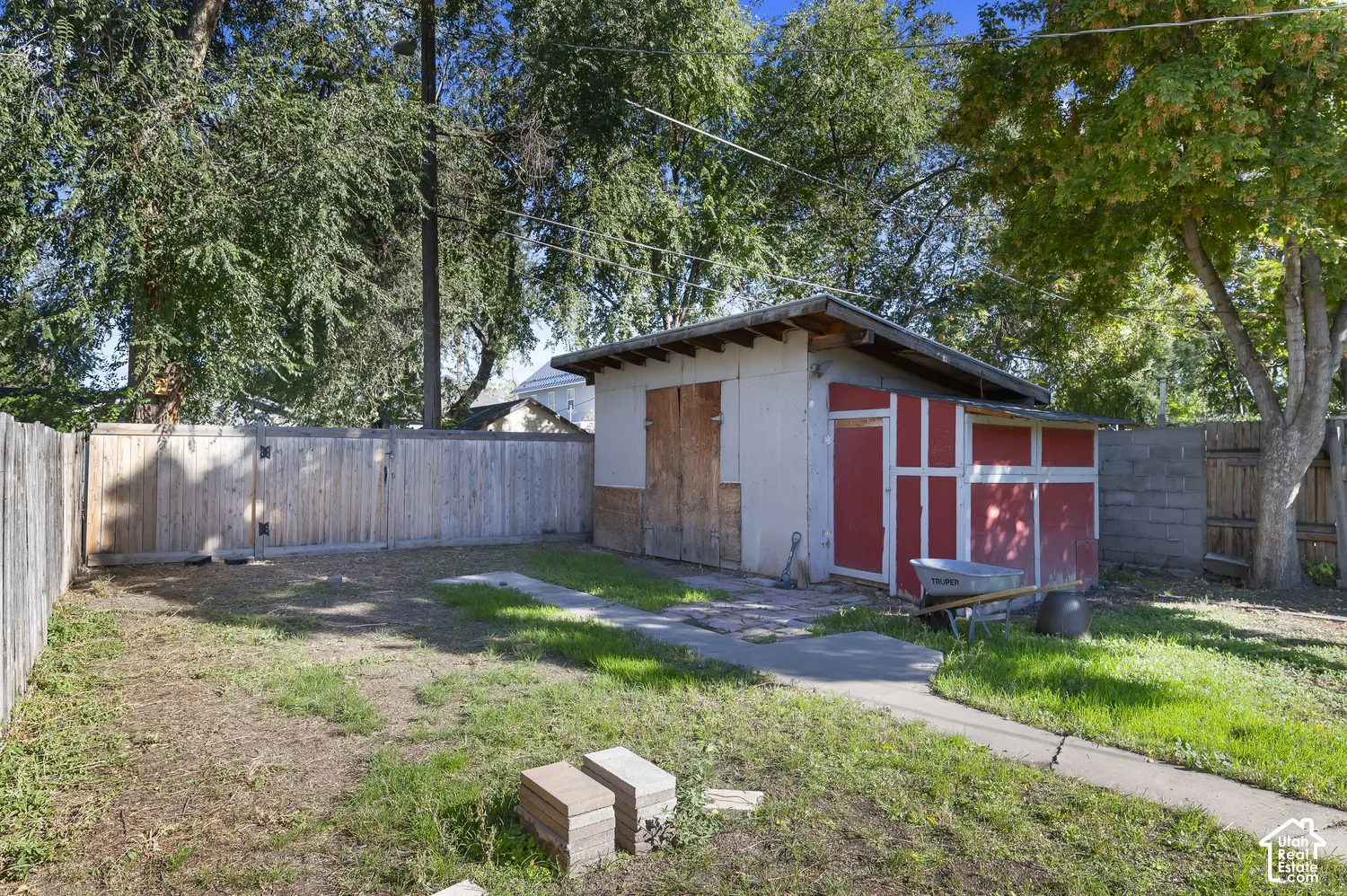 Backyard featuring a shed with a red door, concrete pathway, and a wood fence