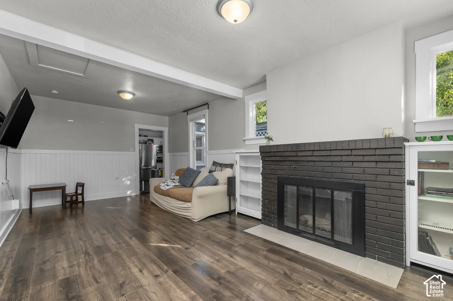 Expansive living area featuring wood-finish flooring, wainscoting, and a brick fireplace