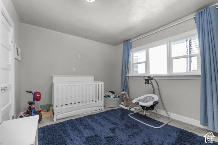 Carpeted room featuring light gray walls, a white paneled door, and a multi-pane window with white trim