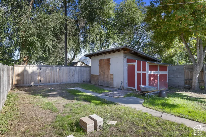 Backyard featuring a shed with a red door, concrete pathway, and a wood fence