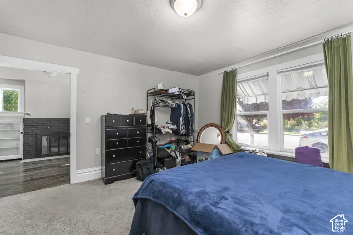 Plush carpeted room featuring multiple windows with natural light, and a doorway opening to a room with wood-finish flooring and a black brick fireplace