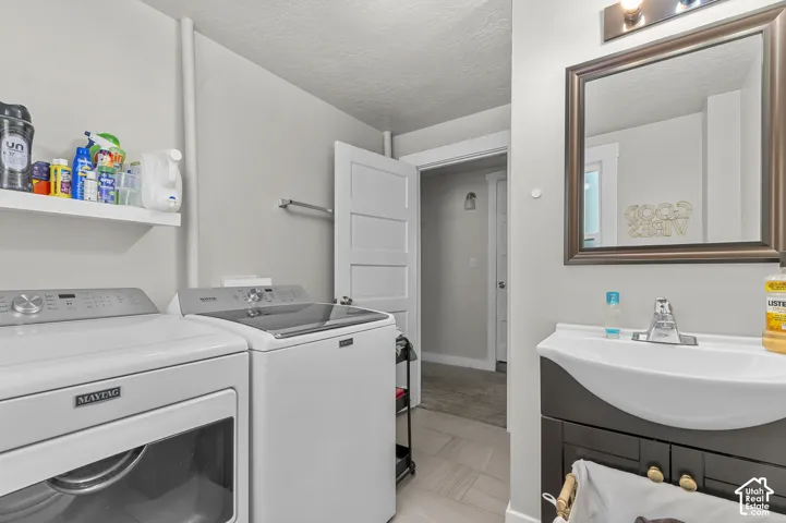 Integrated laundry appliances, wall-mounted shelving, contemporary vanity with an integrated sink, framed wall mirror, and modern lighting fixture
