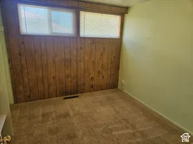 Carpet flooring, wood-panel accent wall, painted walls, and window with blinds