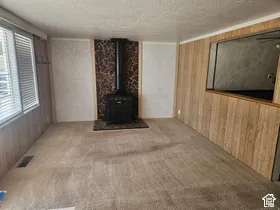 Built-in wood-burning stove with stone surround, wood-finish wall paneling, and wall-to-wall carpeting