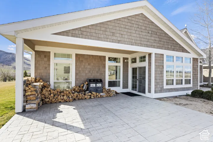 Charming cottage-style home featuring a spacious covered front porch with white trim and substantial columns, cedar shake siding, and multiple multi-pane windows