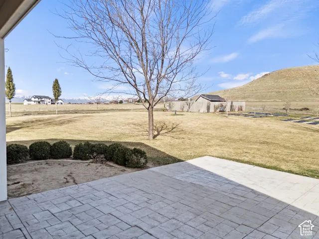 Expansive backyard with mature landscaping, manicured lawn, and professional hardscape patio featuring geometric pavers