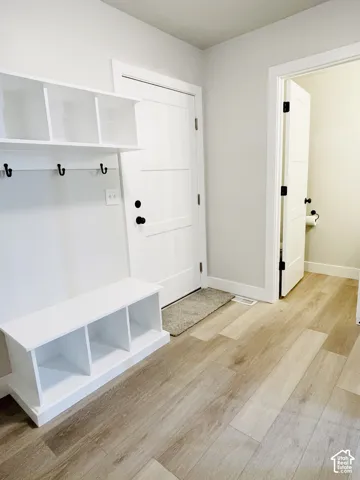 Wood-finish flooring, built-in storage bench, and white paneled doors with matte black hardware