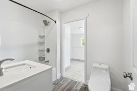 White vanity with integrated sink, brushed nickel faucet, and wood-finish flooring