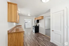 Wood-finish flooring, wood cabinetry, built-in microwave, and stainless-steel range