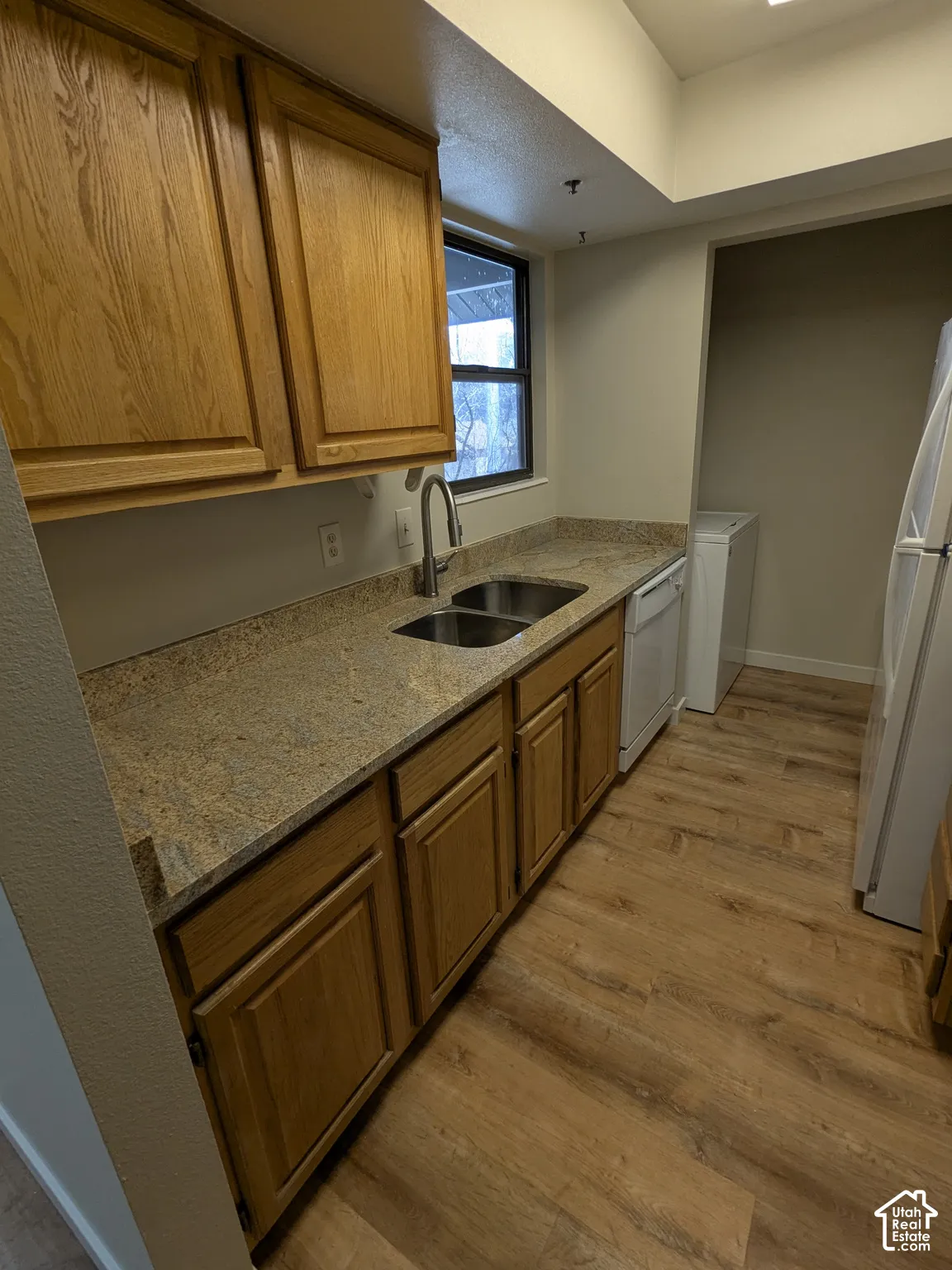 Wood-finish flooring, solid surface countertops, double basin sink with gooseneck faucet, and wood cabinetry