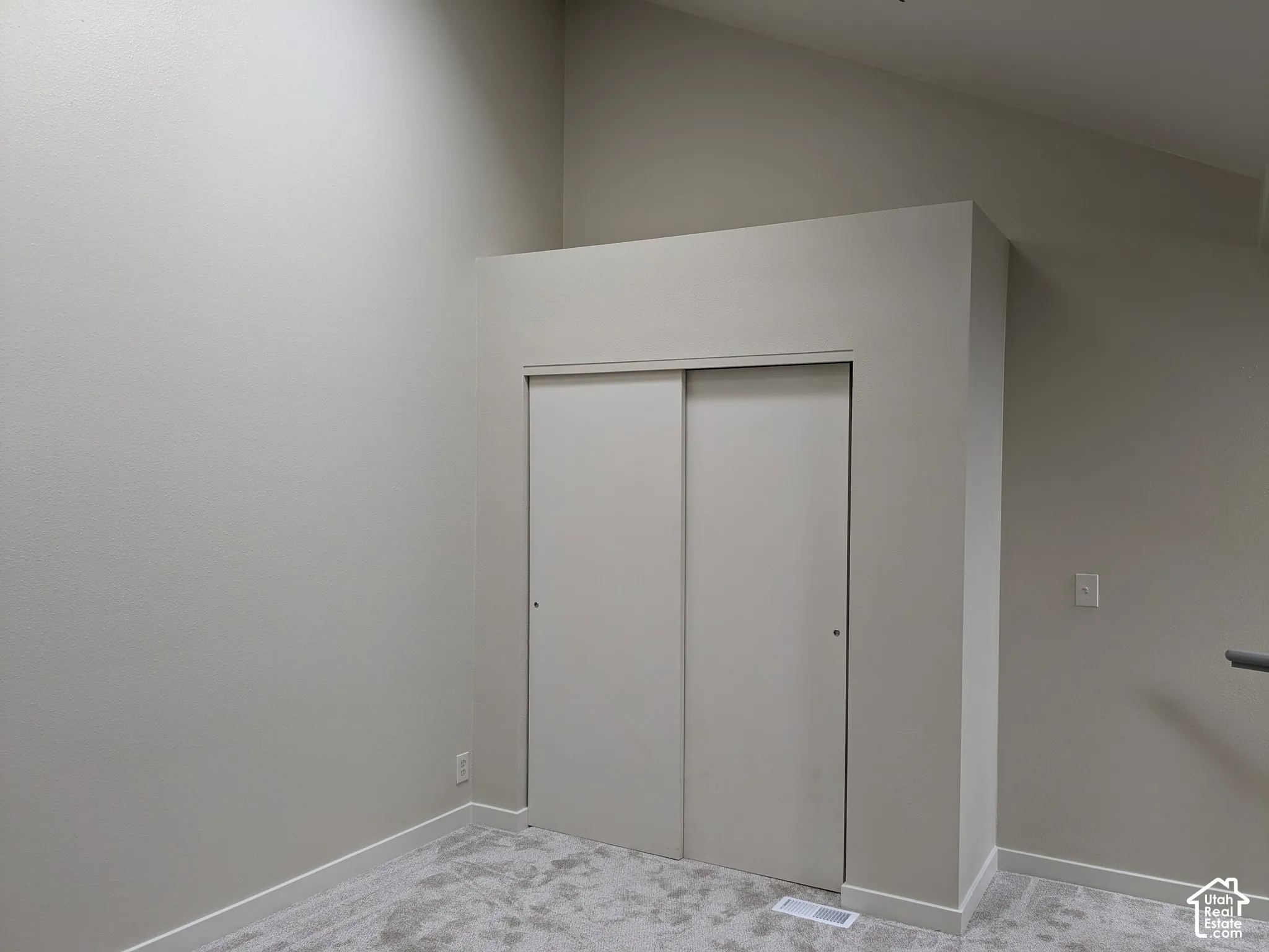 Vaulted ceiling, neutral tone walls, sliding closet doors, and light-toned carpet