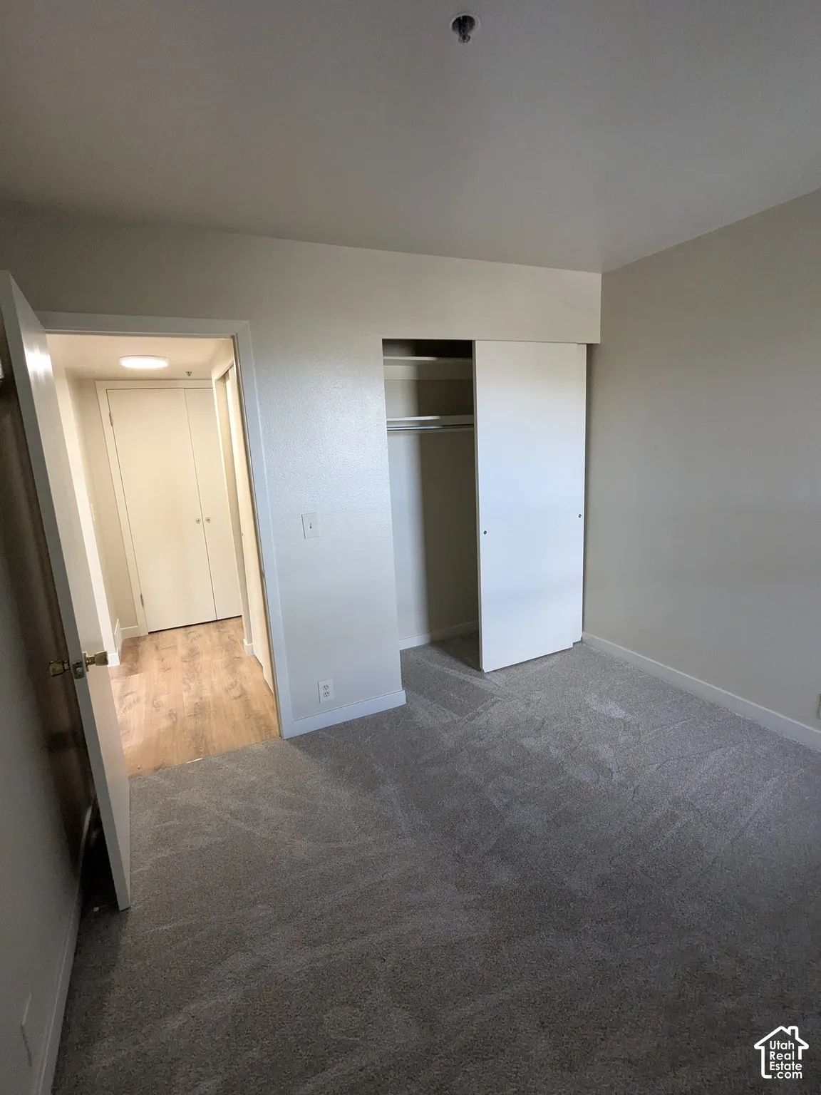 Spacious bedroom featuring neutral wall finishes, carpeted flooring, and a reach-in closet with shelving
