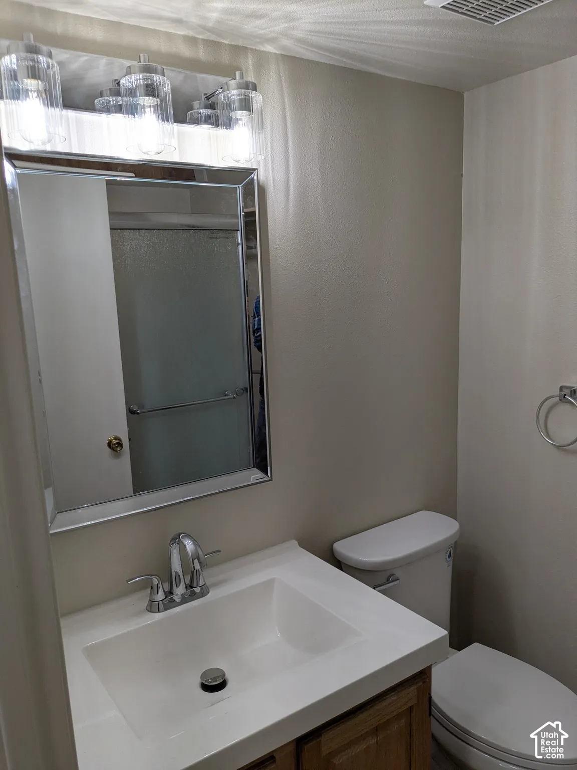 Vanity with integrated sink, chrome faucet, framed mirror, and a three-light fixture