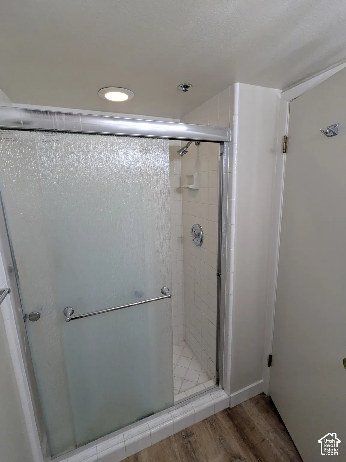 Shower enclosure featuring sliding frosted glass doors, a tile surround, and a chrome shower head and fixtures