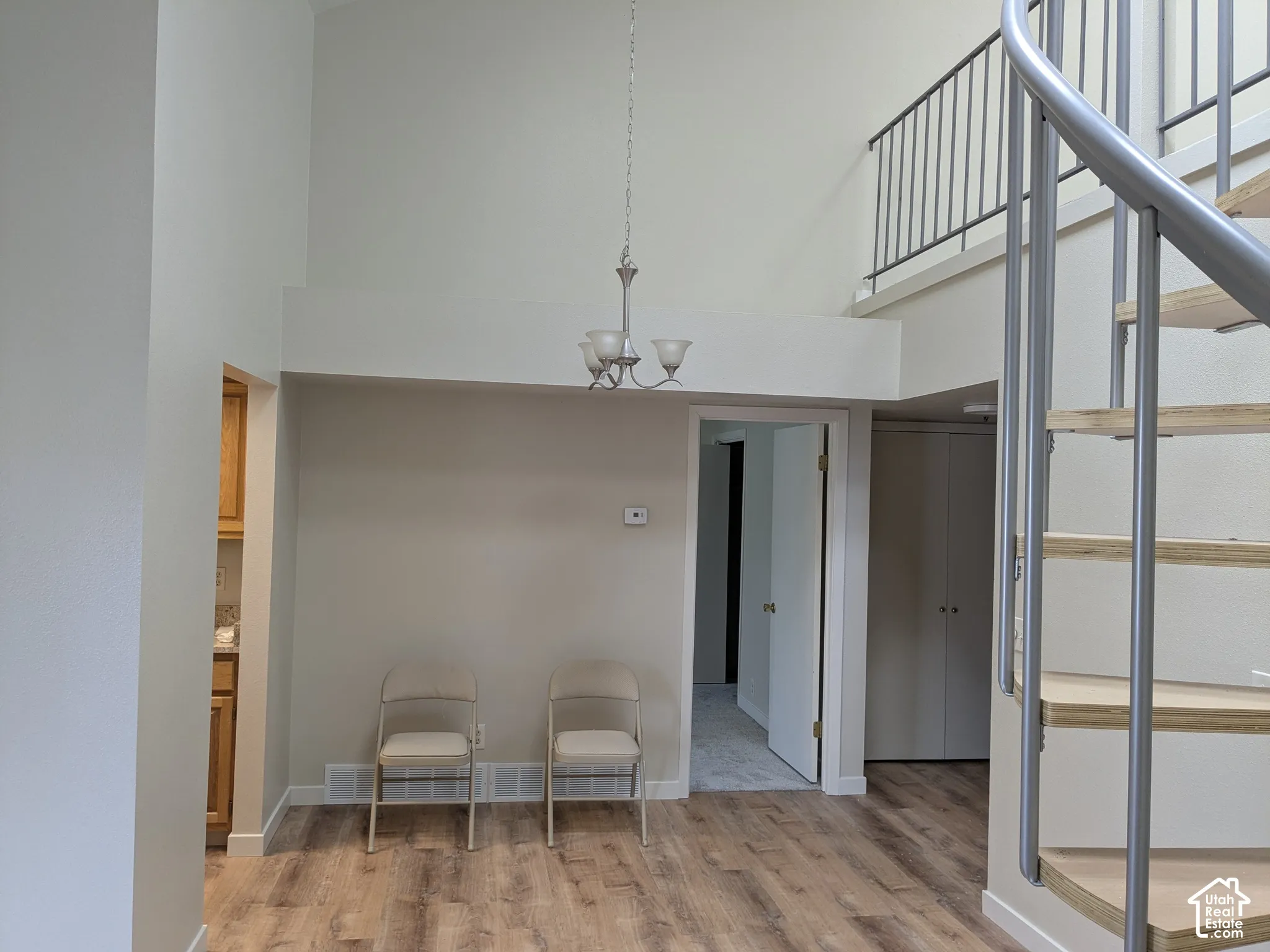 Vaulted ceiling with chandelier, spiral staircase, wood-finish flooring, interior balcony with railing, built-in closet