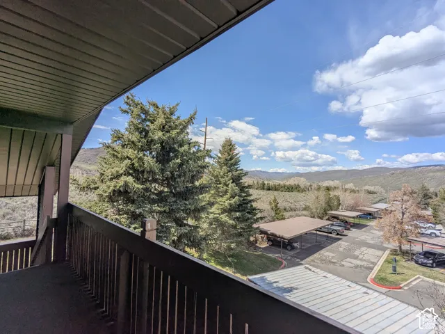 Balcony featuring a solid railing, dark wood-finish ceiling, and mountain scenery