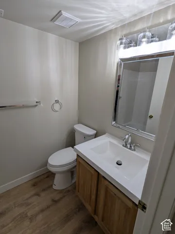 Bathroom featuring a wood-finish vanity with an integrated white sink, chrome faucet, wall-mounted mirror, and overhead vanity lighting