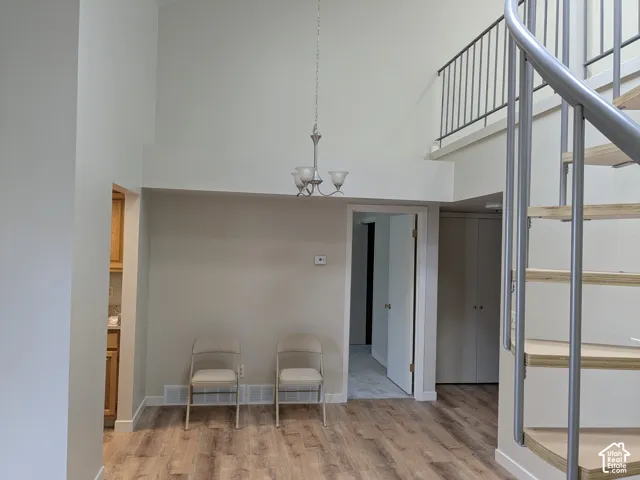 Vaulted ceiling with chandelier, spiral staircase, wood-finish flooring, interior balcony with railing, built-in closet