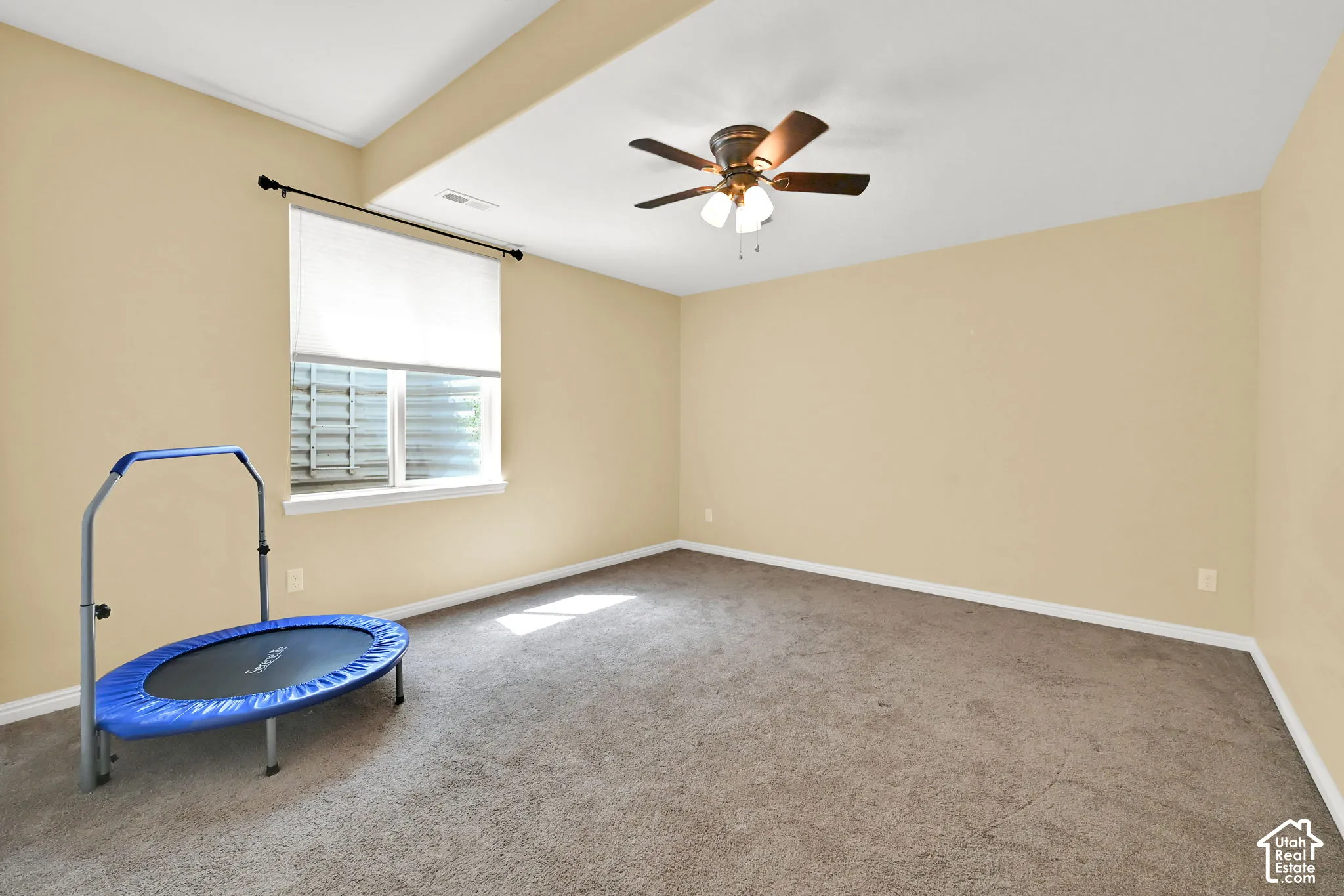 Carpeted interior space with a window, ceiling fan, and recessed ceiling area
