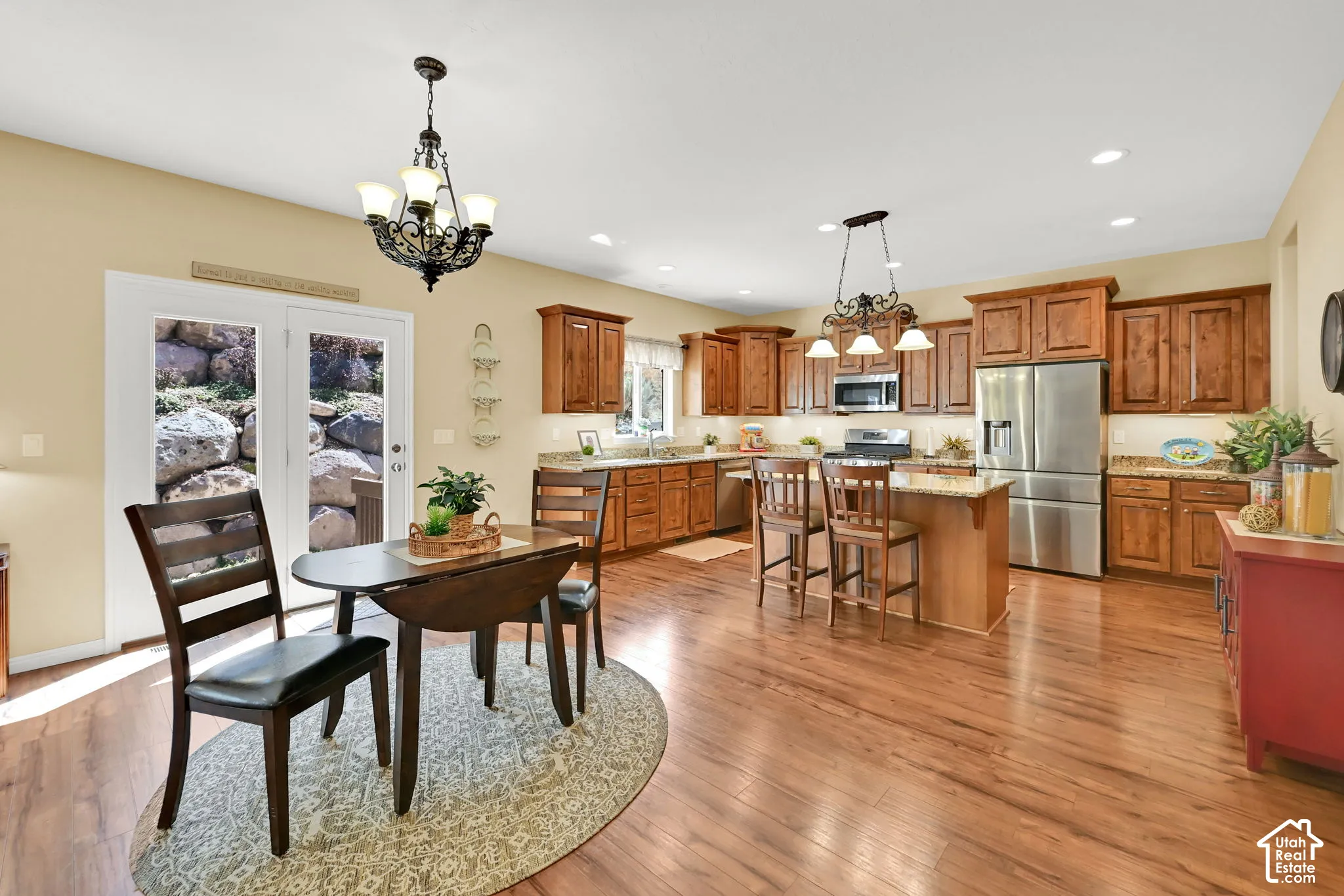 Open-concept kitchen and dining area featuring wood-finish flooring, recessed lighting, wood cabinetry, and stainless steel appliances