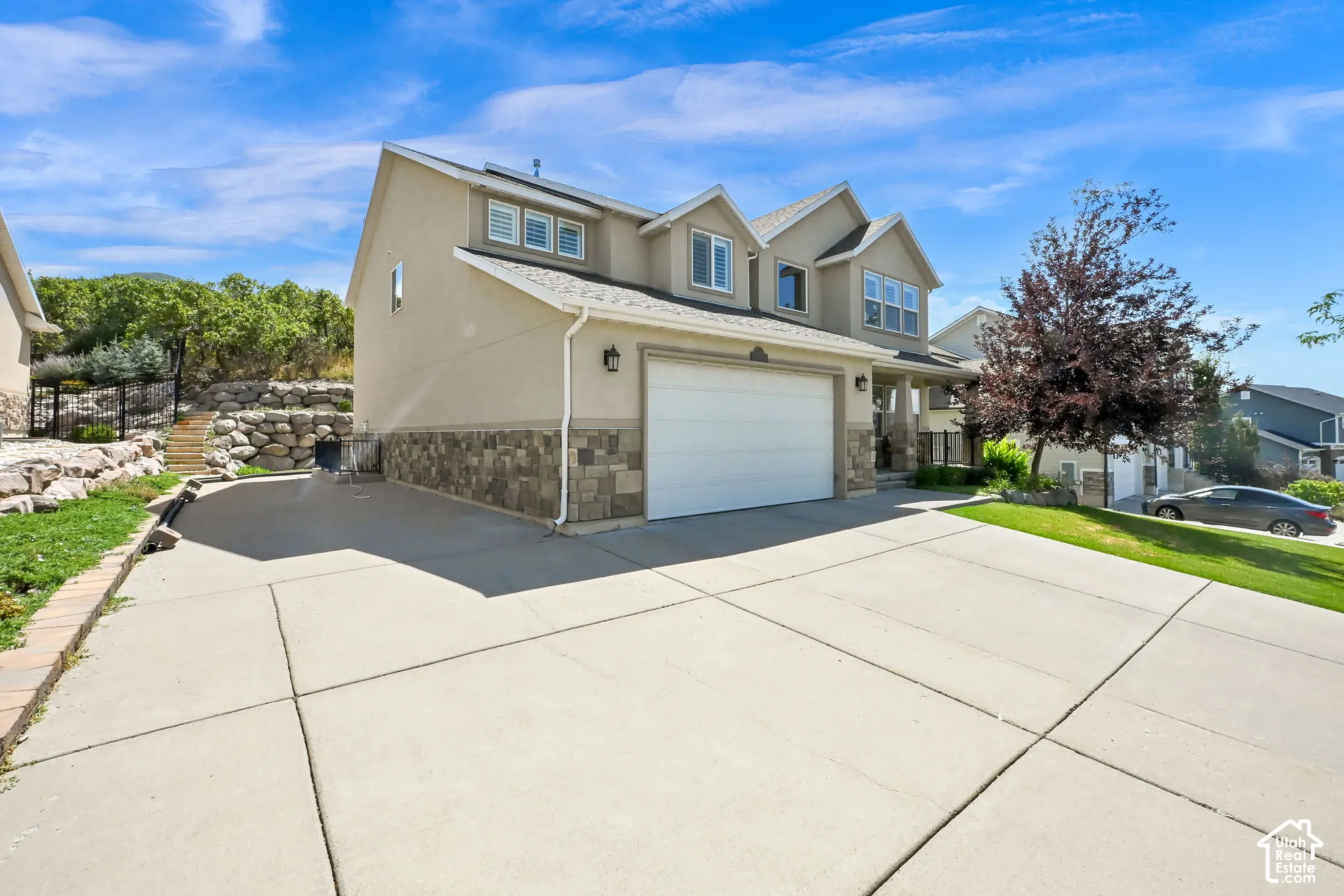 Stucco exterior with stone veneer accents, multi-pane windows, and an attached garage