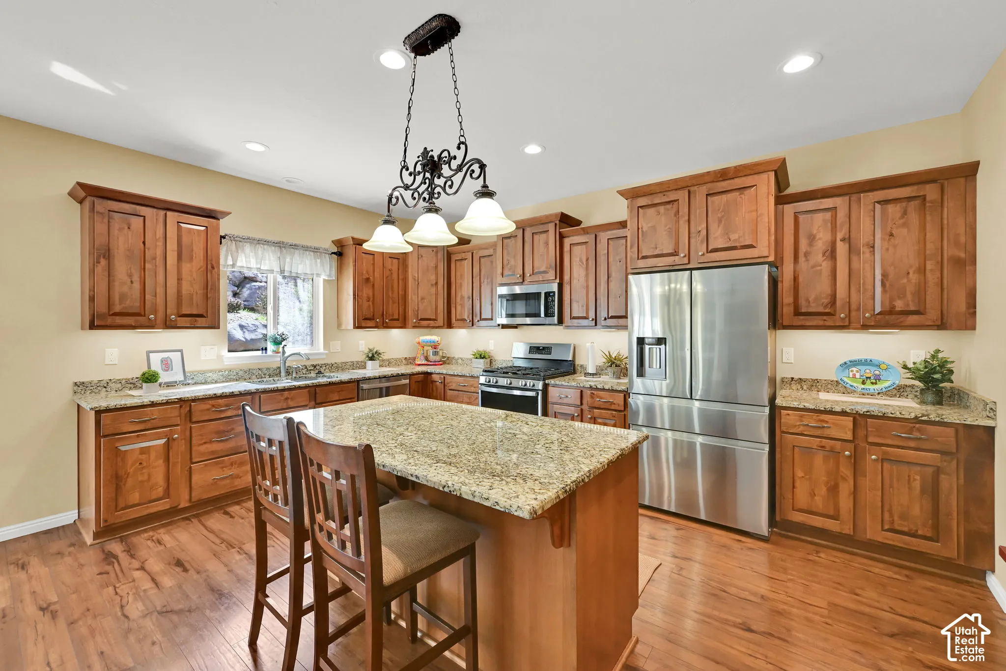 Kitchen featuring wood-finish flooring, recessed lighting, a central island with a granite countertop, and stainless steel appliances