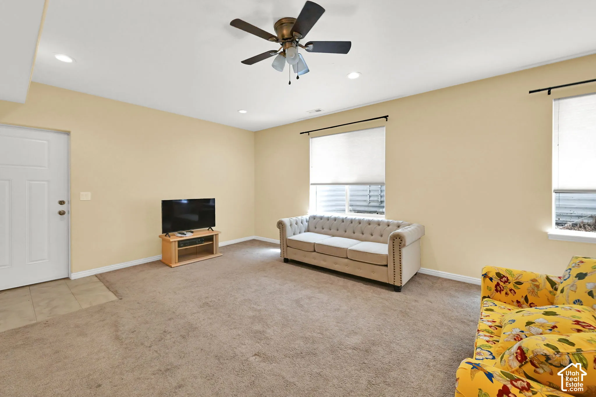 Recessed ceiling lighting, ceiling fan, two windows, carpet flooring, and a white interior door
