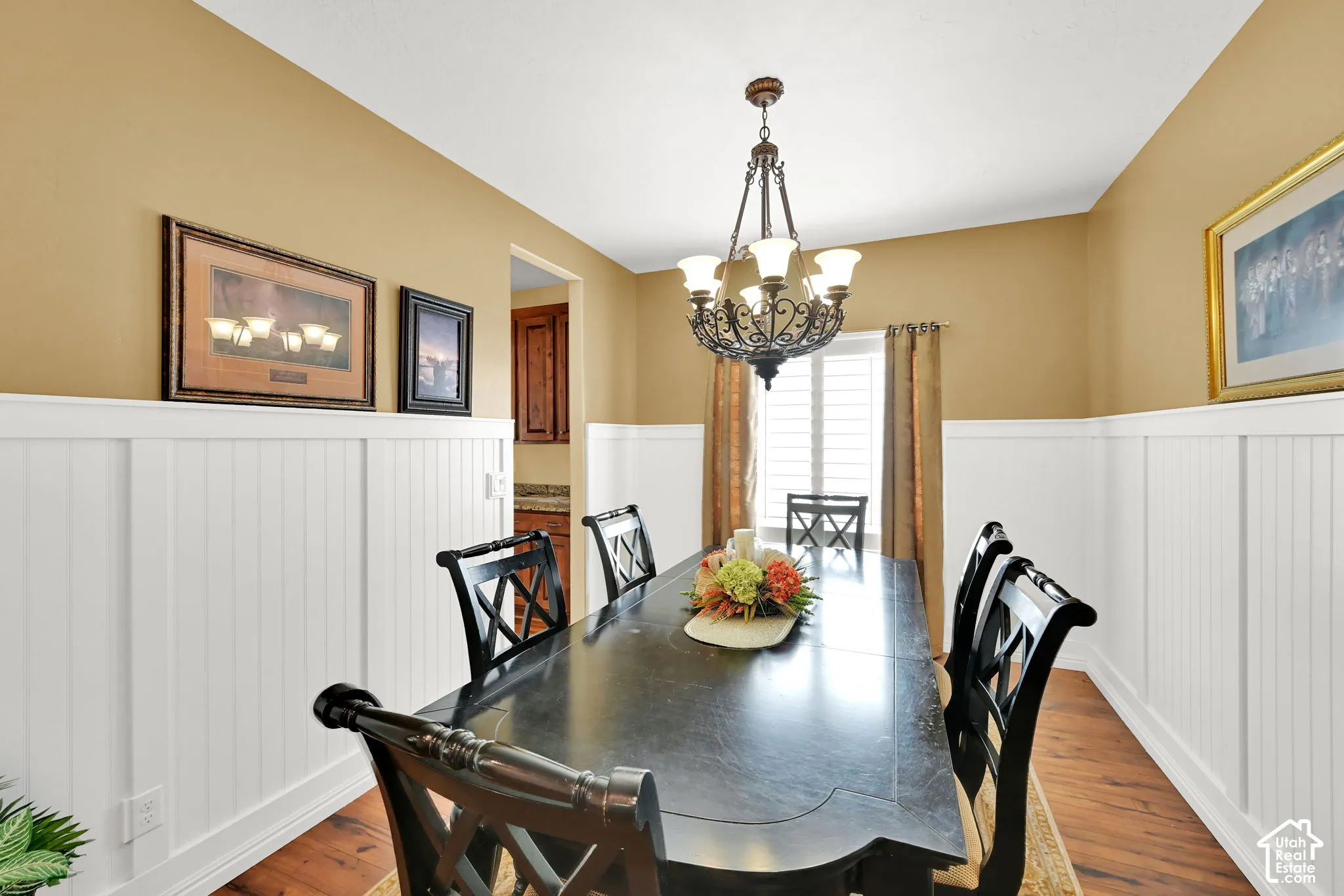 Wood-finish flooring, wainscoting paneling, and an ornate chandelier