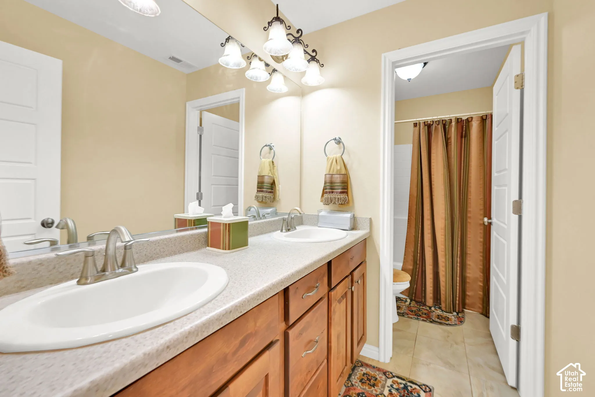 Dual sinks with brushed nickel fixtures, wood-finish cabinetry, and a large vanity mirror