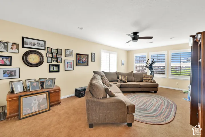 Recessed lighting, ceiling fan, multiple windows with plantation shutters, and carpeted flooring