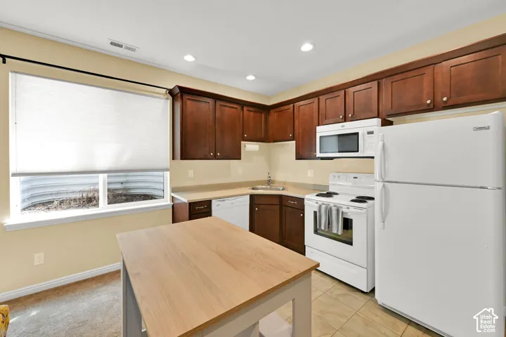 Kitchen featuring cabinetry with crown molding, white appliances, and a stainless steel sink