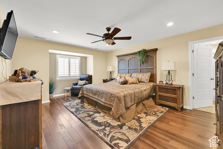 Recessed lighting, wood-finish flooring, ceiling fan, window with white plantation shutters, and a white paneled door