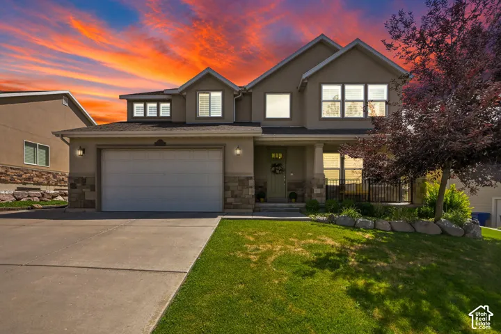 Stucco exterior with stone accent detailing, attached garage, covered porch, and concrete driveway