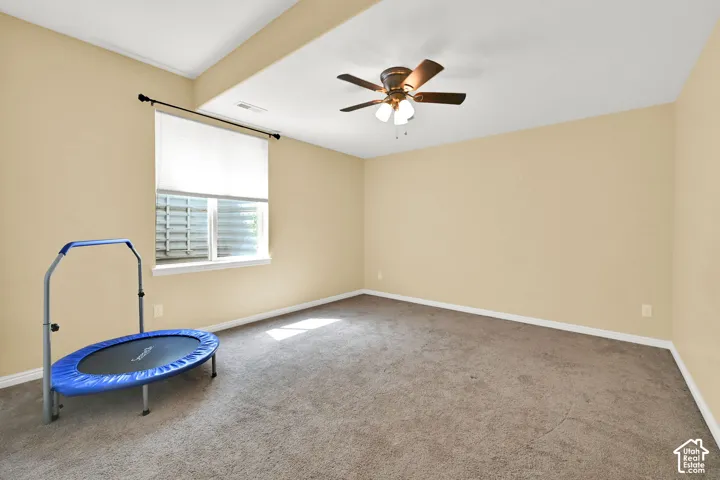 Carpeted interior space with a window, ceiling fan, and recessed ceiling area