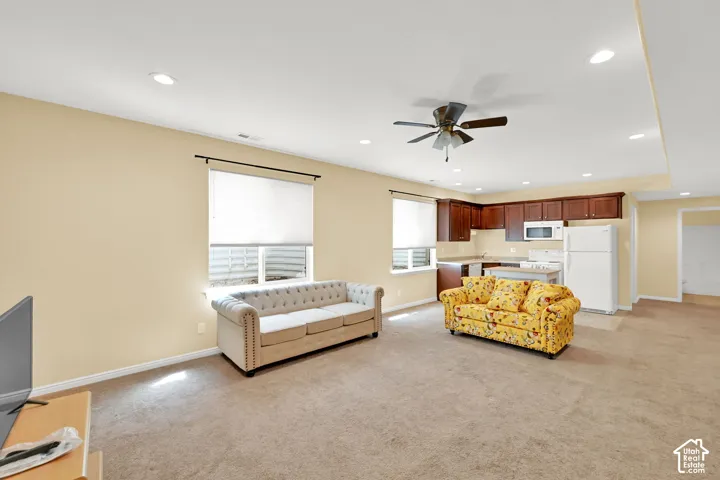 Recessed ceiling lighting, ceiling fan, carpet flooring, full kitchen with wood cabinetry and white appliances, and window with privacy blind